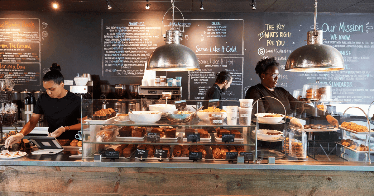 Restaurant employees working behind a busy café counter, illustrating restaurant staffing shortages and the demands of daily service