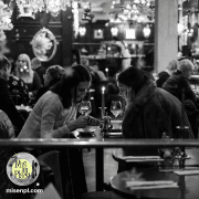 House ad: black-and-white photo of guests talking across a bar