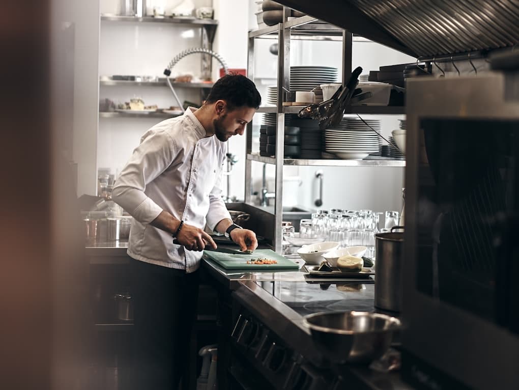 Chef plating a dish on a restaurant pass