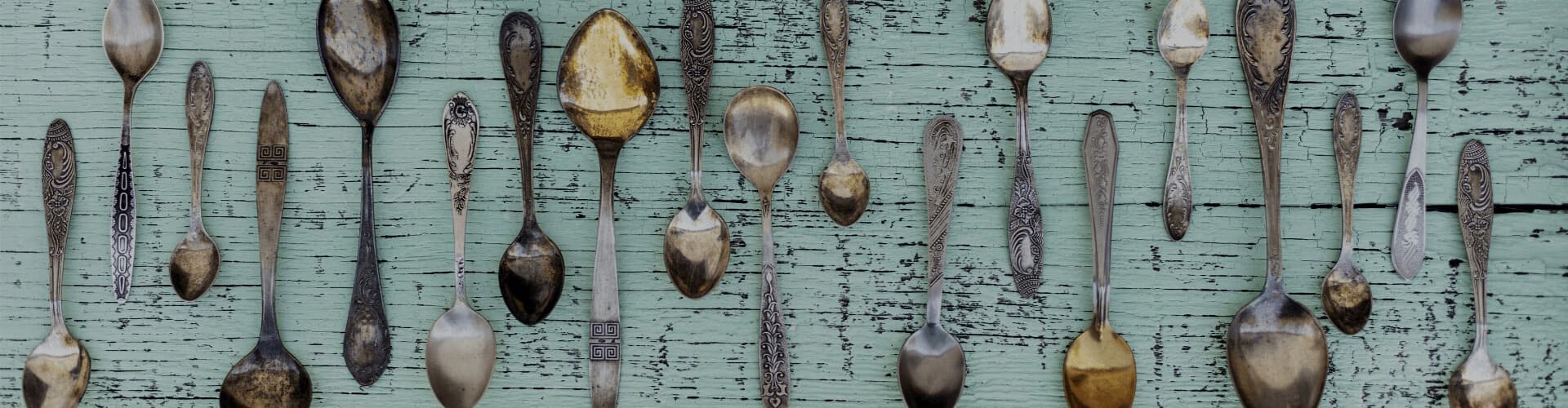 Antique spoons laid out on weathered mint green boards