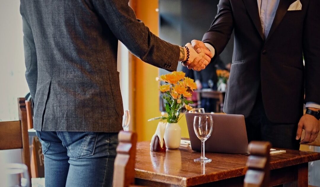 Two people shaking hands in a restaurant, representing mutual agreement on restaurant hiring expectations